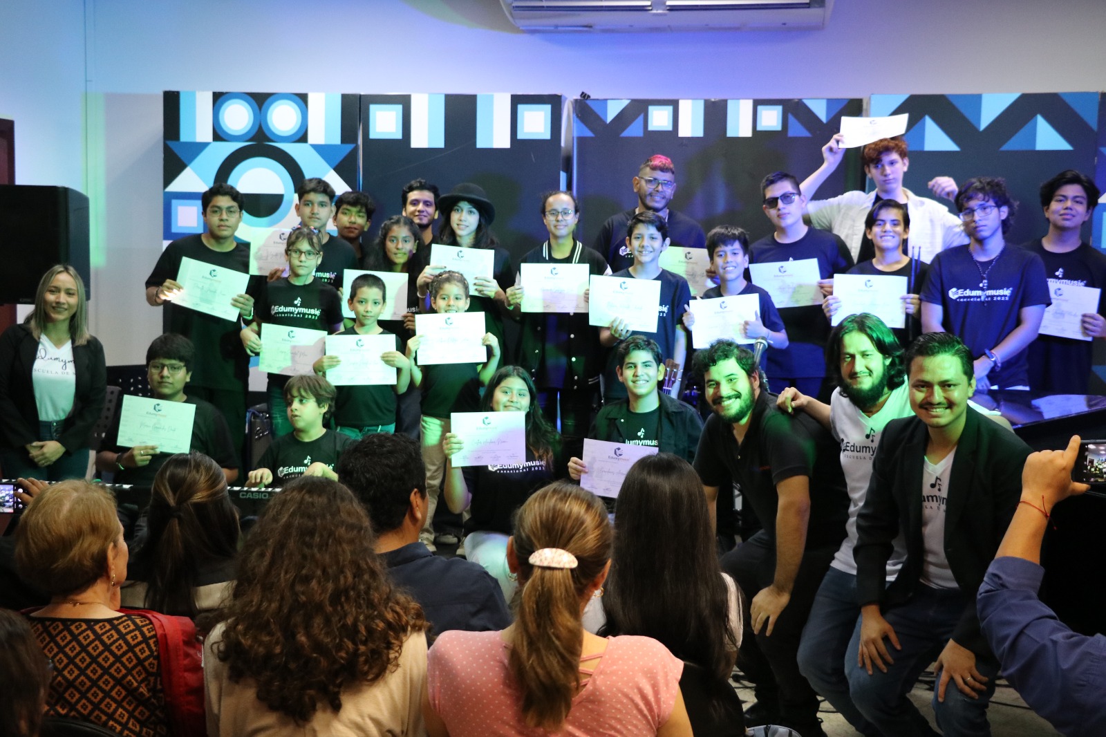 Los 24 alumnos del trimestre con sus certificados, frente a sus familias